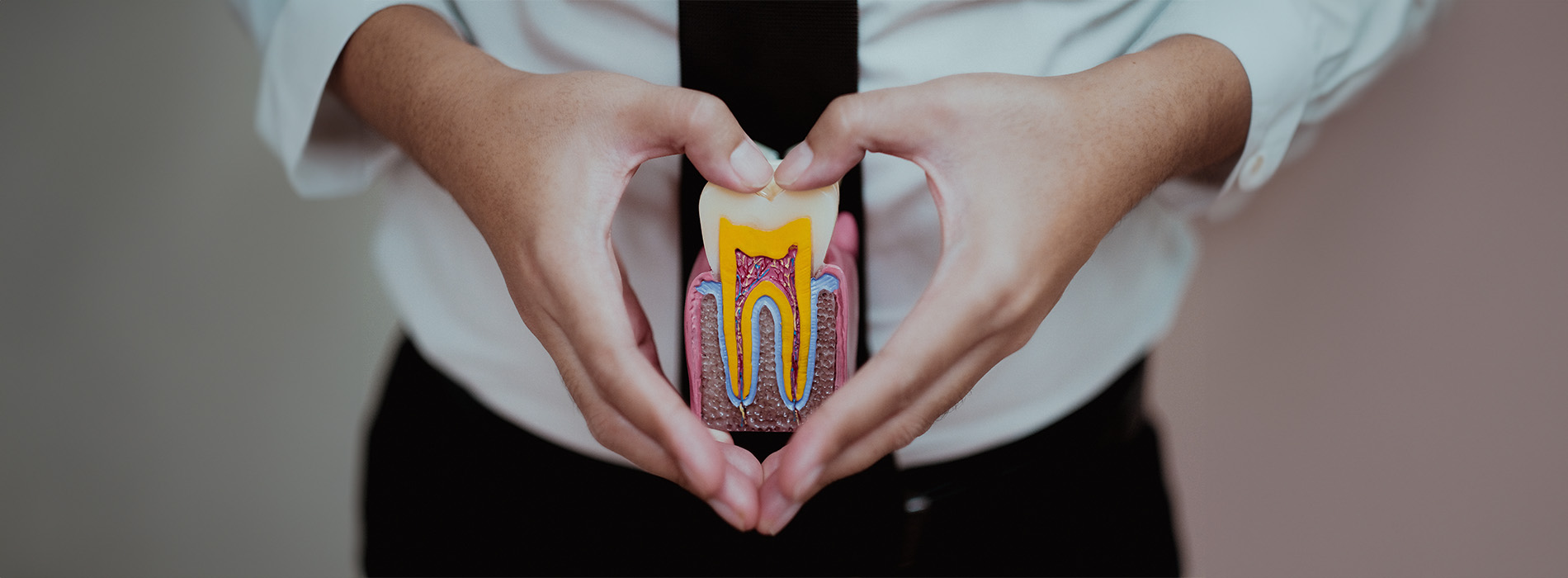 A person is seated in a dental chair, receiving care from a dental professional who stands behind them.